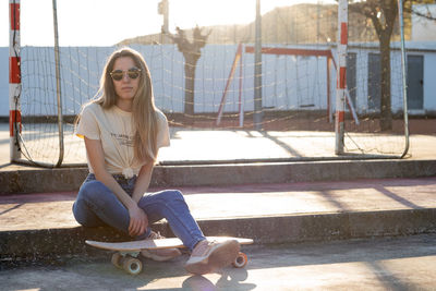 Portrait of young woman sitting on footpath