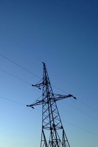 Low angle view of electricity pylon against blue sky