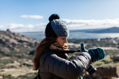 Woman holding camera while standing outdoors