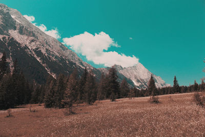 Scenic view of field by mountains against sky