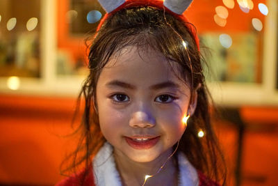 Close-up portrait of cute girl with string lights