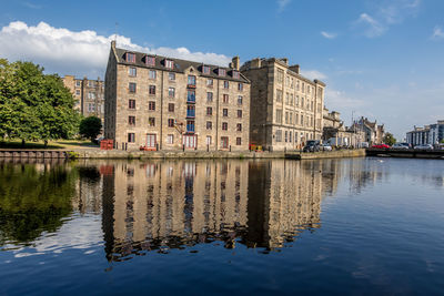 Reflection of buildings in lake against sky in city