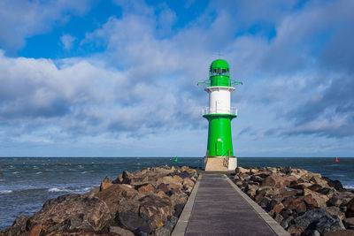 Lighthouse by sea against sky