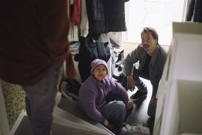 High angle view of gay couple with daughter sitting near house entrance