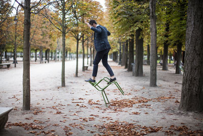 Full length of businessman playing on chair at park