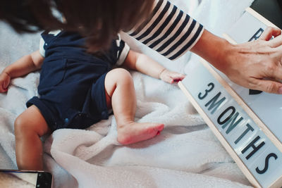 High angle view of mother hand by toddler on bed