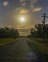 Road amidst field against sky during sunset