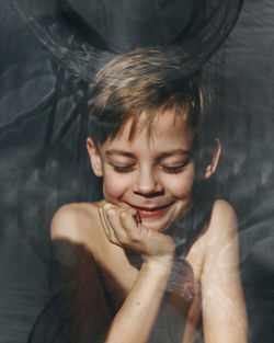 Close-up of shirtless boy smiling seen through glass