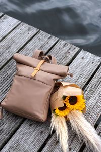 Traveler's backpack and a bunch of sunflowers lie on a pier.