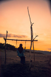 Rear view of silhouette person on beach during sunset