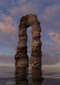 Rock formation in sea against sky during sunset