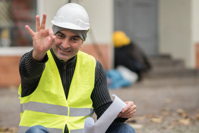 Portrait of architect gesturing ok sign at construction site