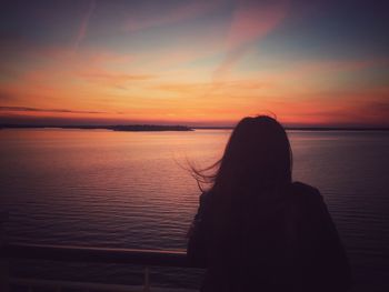 Silhouette woman by sea against sky during sunset