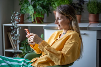 Interested glad smiling woman sitting, holding mobile phone, messaging, chatting with boyfriend