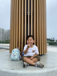 Cute asian boy sitting on chair in playground 