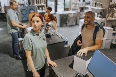 Mature man talking with saleswoman at checkout counter in appliances store