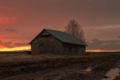 House on field against sky during sunset