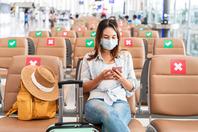 Woman wearing mask using mask sitting at airport