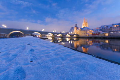 Illuminated bridge over river against sky during winter