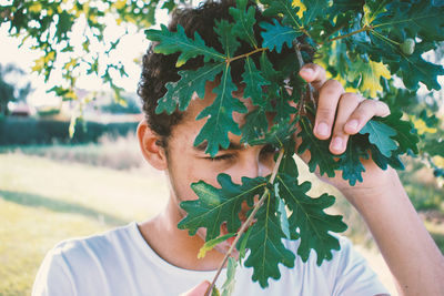 Close-up portrait of man with leaves outdoors