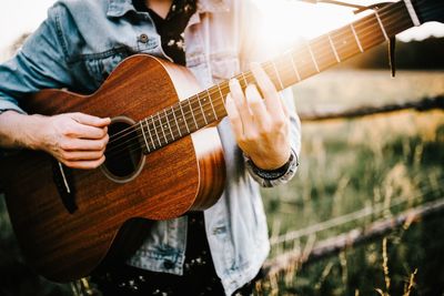 Midsection of man playing guitar