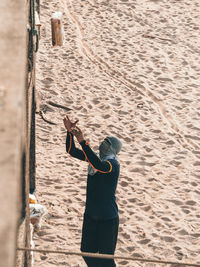 Man covering face catching package while standing on sand