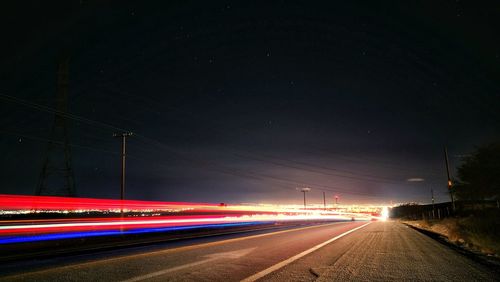 Light trails on road against sky at night