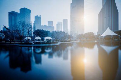 Scenic view of lake by buildings against sky in city