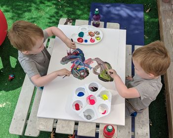 High angle view of siblings drawing on picnic table