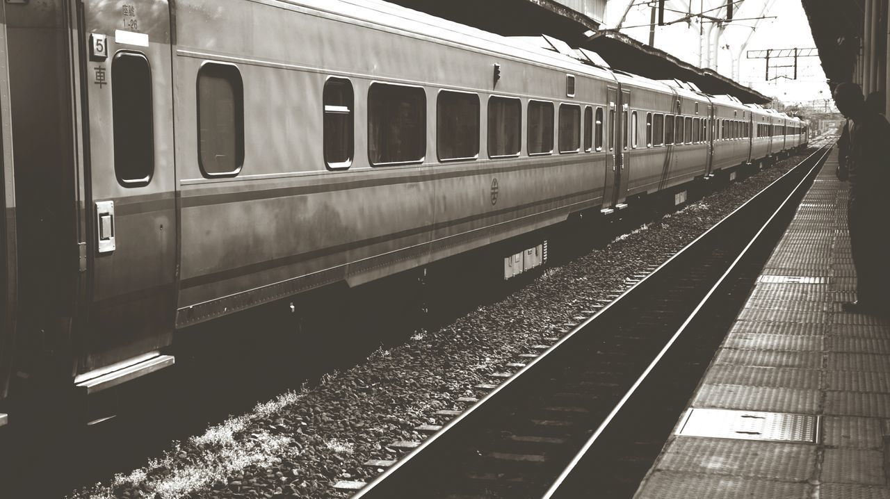 architecture, built structure, railroad track, rail transportation, transportation, public transportation, building exterior, railroad station, railroad station platform, city, train - vehicle, building, low angle view, train, no people, railing, incidental people, mode of transport, day, diminishing perspective