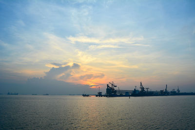 Silhouette built structure on sea against sky during sunset