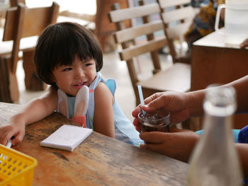 Cropped hand of person giving cold drink to girl at cafe