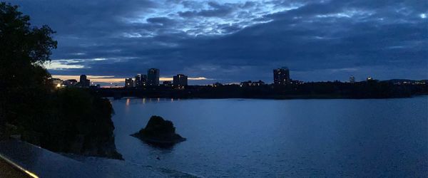 Scenic view of lake by buildings against sky at dusk