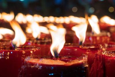Close-up of illuminated burning candles in temple