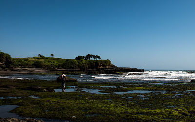 People on beach against clear sky