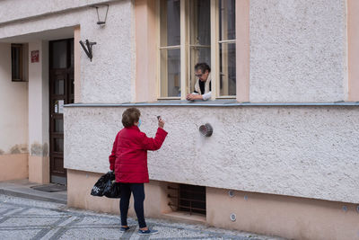 Rear view of woman standing against building