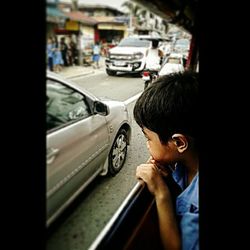 Rear view of man holding car on street