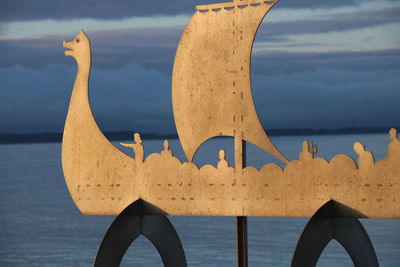 Close-up of deck chairs on beach against sky