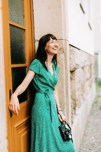 Smiling young woman standing by door