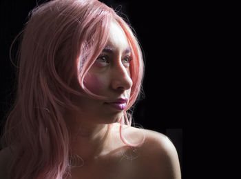 Close-up of young woman against black background