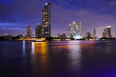 Illuminated buildings in city against sky at night