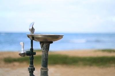 Close-up of metal structure on beach against sky