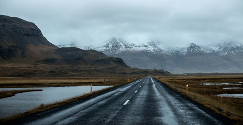 Road leading towards mountain against sky