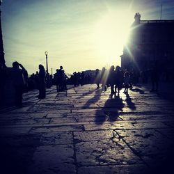 People walking on city street at sunset