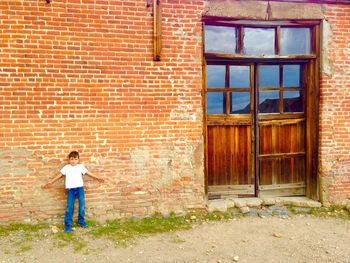 Portrait of boy standing against brick wall