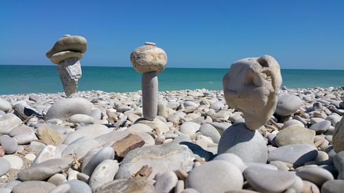 Pebbles on beach against clear blue sky