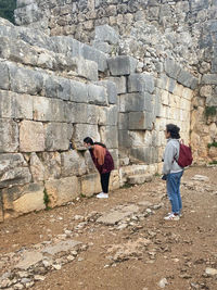 Rear view of people walking against wall