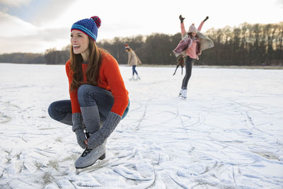 Woman tying her ice skates on frozen lake