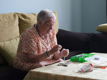 Senior woman making pearl necklace at home