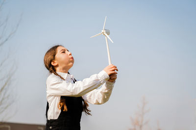 Side view of young woman holding umbrella against sky